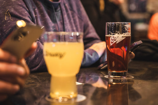 A glass of Go Brewing non-alcoholic beer on a bar table.