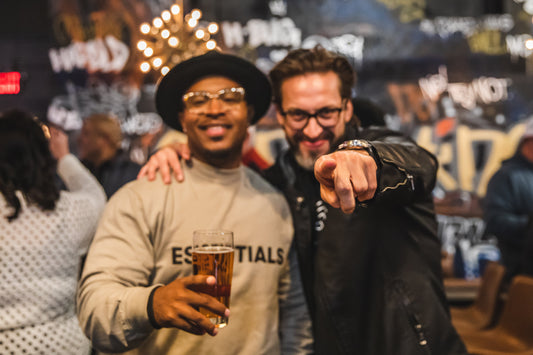 Two friends enjoying non-alcoholic beer at a lively gathering, discussing non-alcoholic beer and liver health benefits.