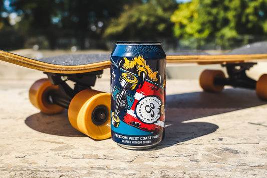 A can of gluten free beer beside a skateboard, showcasing its vibrant design and full flavor profile.